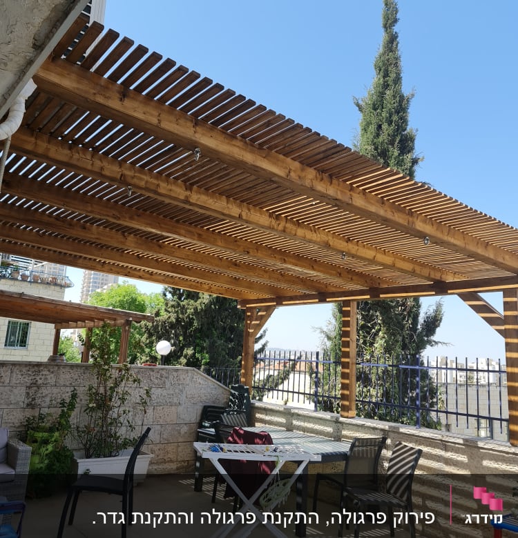 פרגולה מעץ עם כיסאות ושולחן בגינה